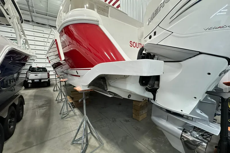 Slide: The Image of 2020 Intrepid 475 Sport Yacht in storage, featuring red and white hull, outboard engines. - 28