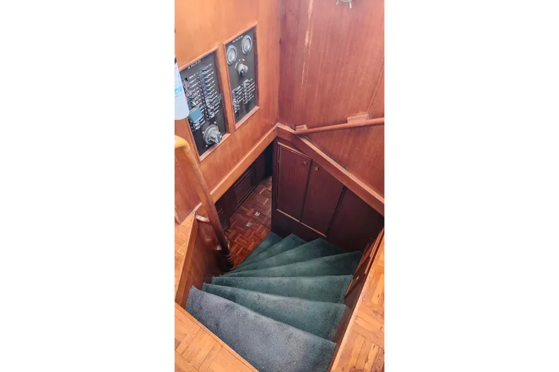 Slide: The Image of Interior staircase of 1979 Marine Trader 50 Trawler with wooden paneling and green carpet. - 16