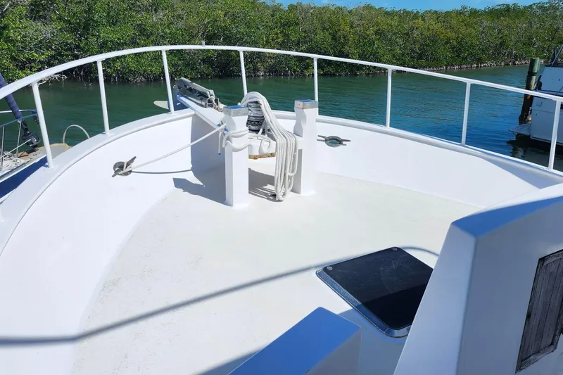 Slide: The Image of 1979 Marine Trader 50 Trawler deck with railing, docked near lush mangroves. - 6