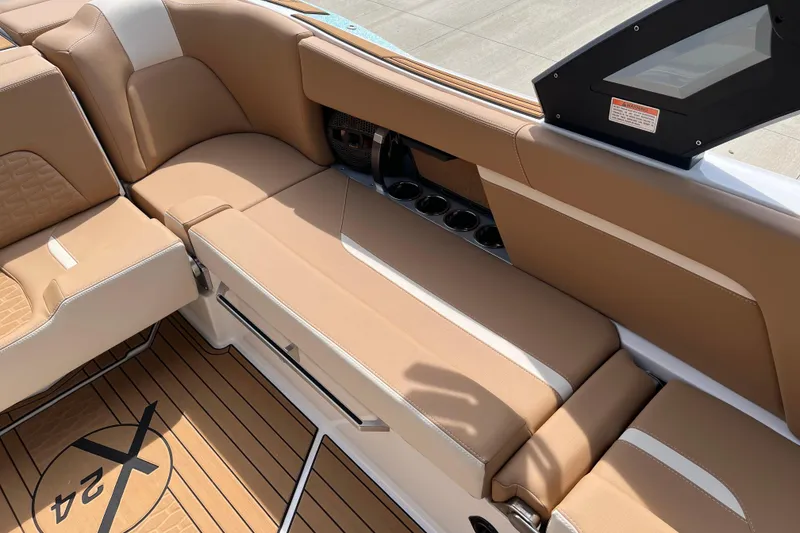 Slide: The Image of 2025 MasterCraft X24 boat interior with tan seating and cup holders. - 12