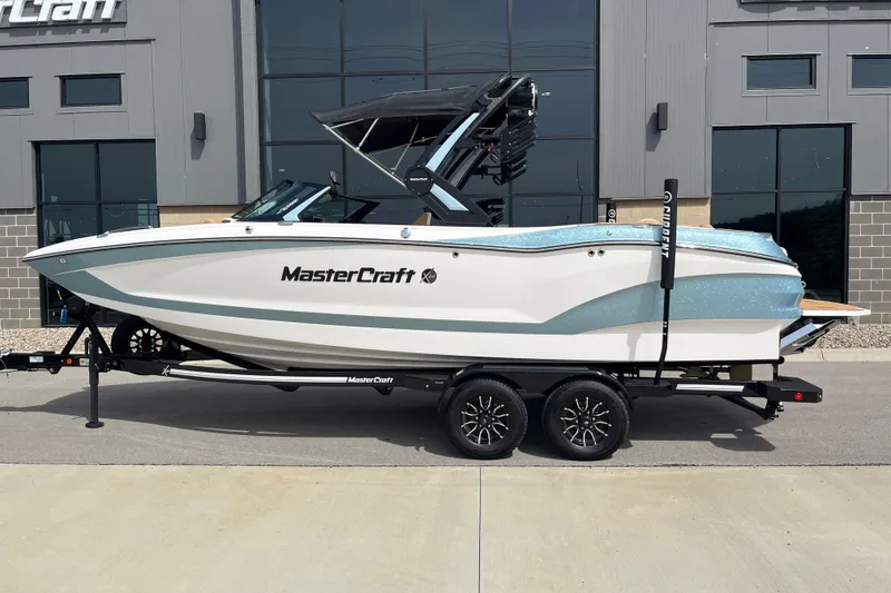Slide: The Image of 2025 MasterCraft X24 boat on trailer, parked outside a modern building. - 3
