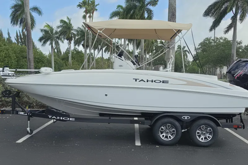The Image of 2026 Tahoe 2150 CC boat with canopy, parked on trailer, surrounded by palm trees. - 0