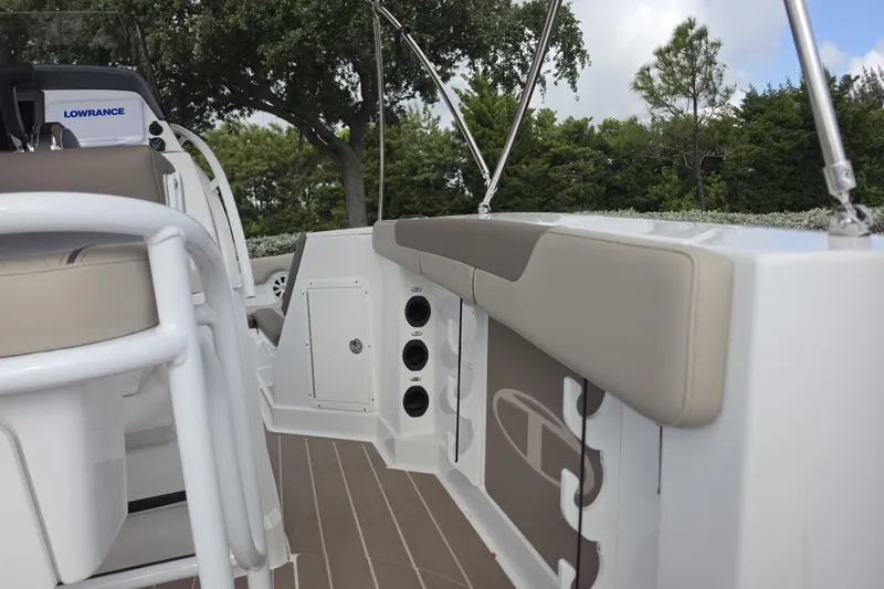 Slide: The Image of 2026 Tahoe 2150 CC boat interior with beige seating and rod holders, featuring Lowrance equipment. - 18