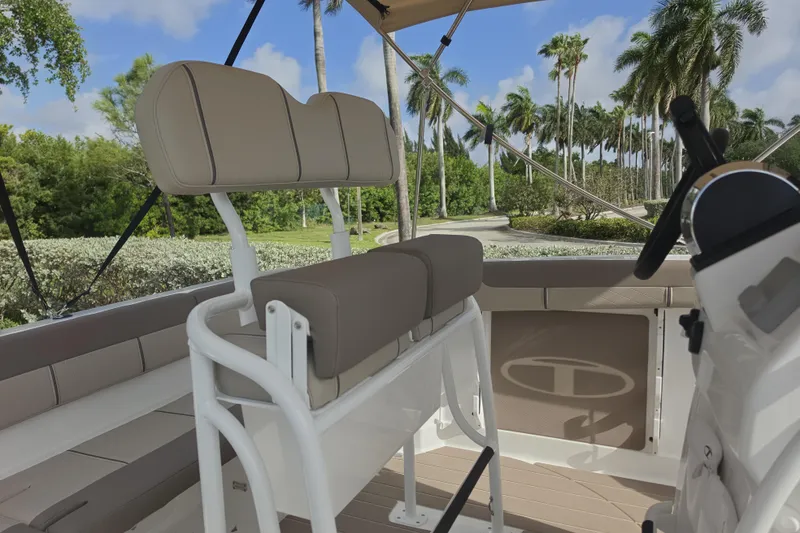 Slide: The Image of 2026 Tahoe 2150 CC boat interior with beige seating and steering, surrounded by palm trees. - 9