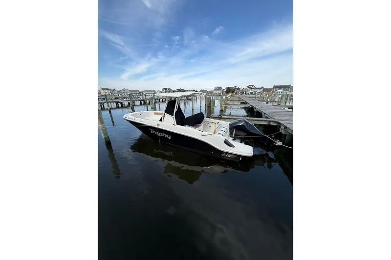 Slide: The Image of 2023 Bayliner Trophy T24CC boat docked at a marina under a clear blue sky. - 2