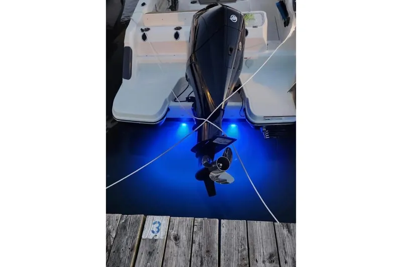 Slide: The Image of 2023 Bayliner Trophy T24CC boat with illuminated blue underwater lights at dock. - 3