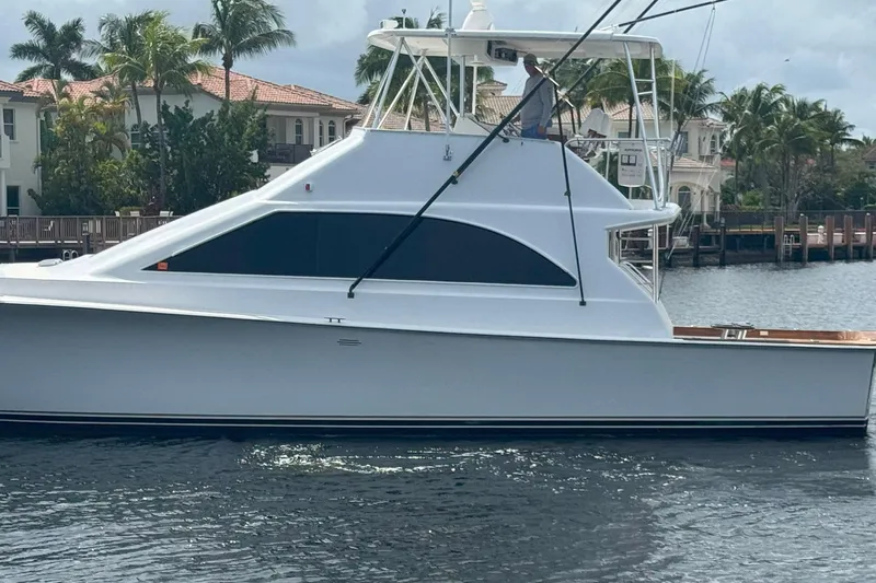 Slide: The Image of 1997 Ocean Yachts 48 Super Sport boat on water, with palm trees and houses in background. - 29