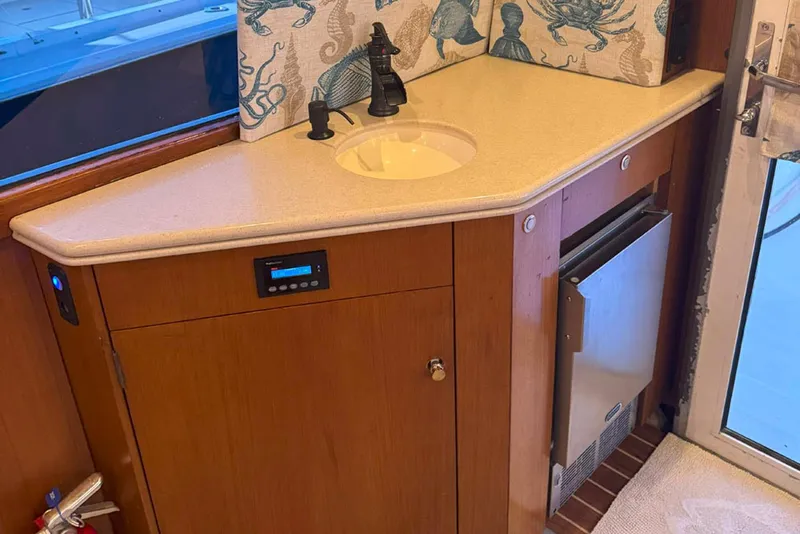 Slide: The Image of 1997 Ocean Yachts 48 Super Sport interior with sink, wooden cabinetry, and nautical-themed decor. - 5