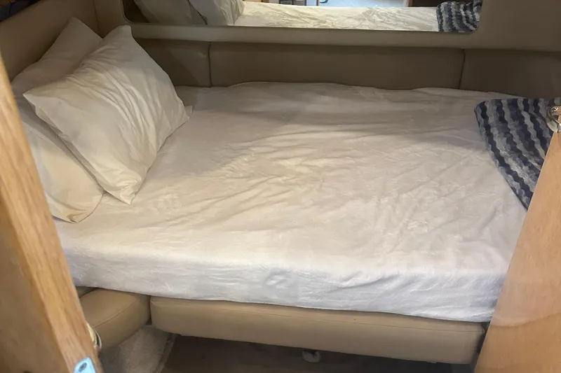 Slide: The Image of 1998 Sea Ray 450 Sundancer cabin with a neatly made bed and pillows. - 14