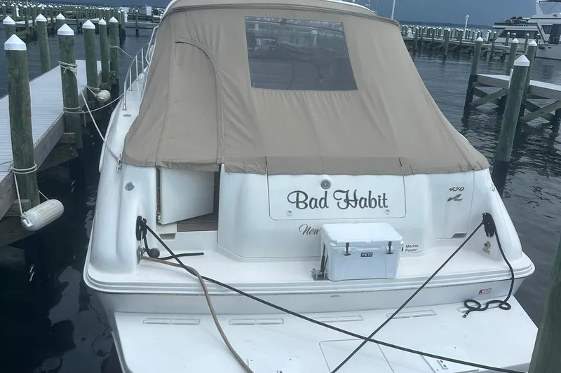 Slide: The Image of 1998 Sea Ray 450 Sundancer docked, rear view with tan cover and cooler. - 30