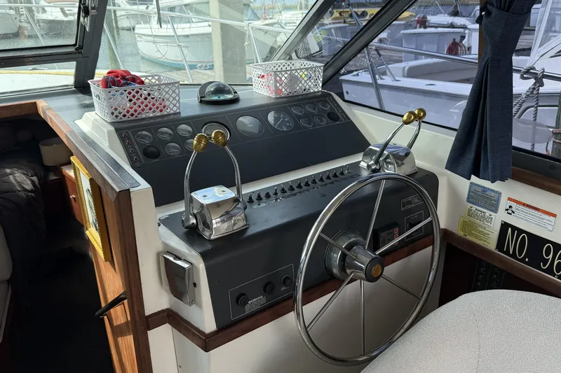 Slide: The Image of 1989 Tiara Yachts 3100 Flybridge helm with steering wheel and control levers. - 17