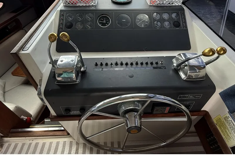 Slide: The Image of 1989 Tiara Yachts 3100 Flybridge helm with steering wheel and control levers. - 18