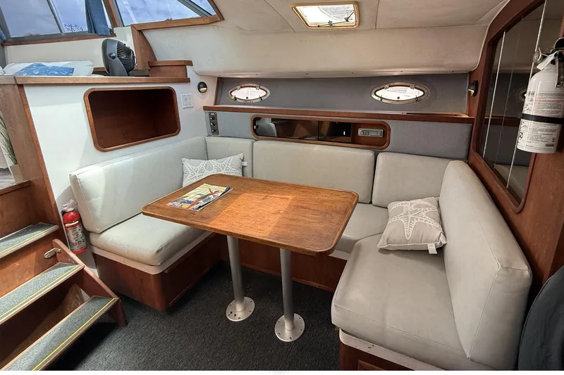 Slide: The Image of 1989 Tiara Yachts 3100 Flybridge interior with cozy seating and wooden table. - 22