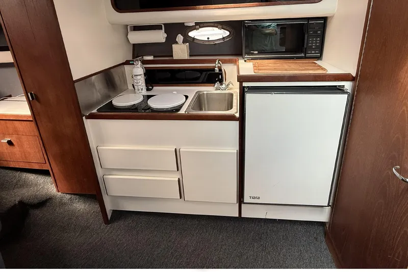 Slide: The Image of 1989 Tiara Yachts 3100 Flybridge kitchen with sink, stove, microwave, and refrigerator. - 23