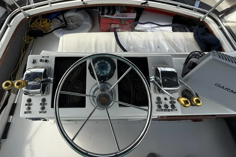 Slide: The Image of 1989 Tiara Yachts 3100 Flybridge helm with steering wheel and navigation controls. - 32