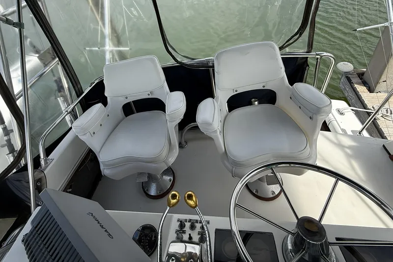 Slide: The Image of 1989 Tiara Yachts 3100 Flybridge helm with dual white captain chairs and steering wheel. - 34