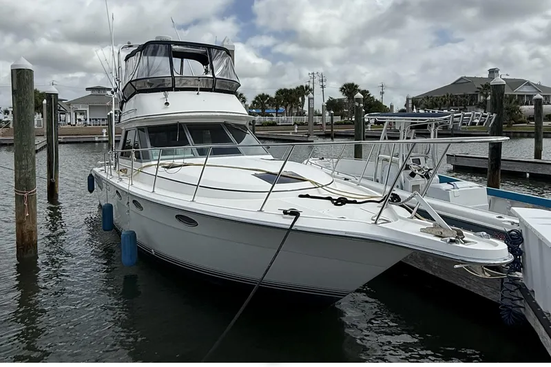 Slide: The Image of 1989 Tiara Yachts 3100 Flybridge docked at marina under cloudy sky. - 4