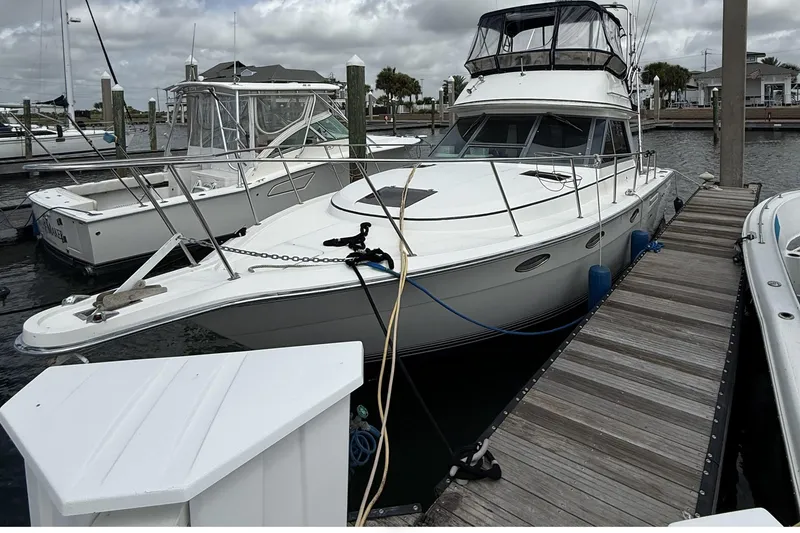 Slide: The Image of 1989 Tiara Yachts 3100 Flybridge docked at marina under cloudy skies. - 6