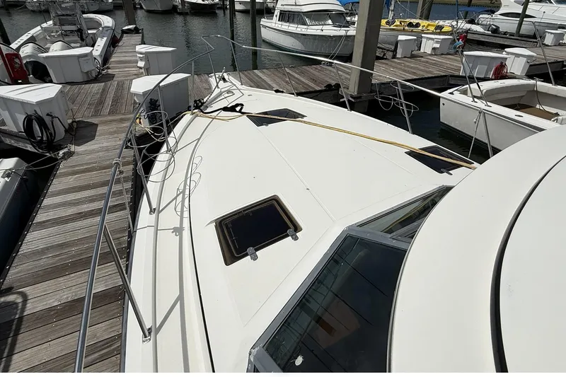 Slide: The Image of 1989 Tiara Yachts 3100 Flybridge docked at marina, showcasing sleek design and spacious deck. - 7