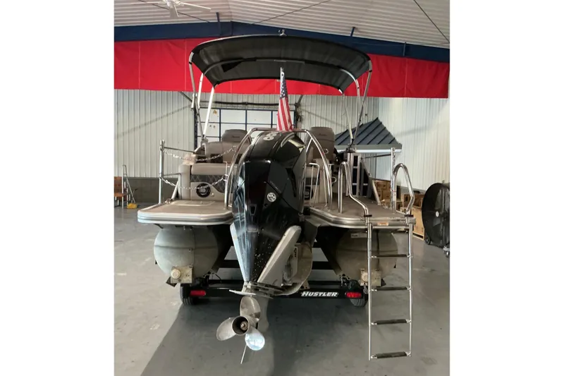 Slide: The Image of 2021 Barletta L23UC pontoon boat in a garage, featuring a sleek design and outboard motor. - 18