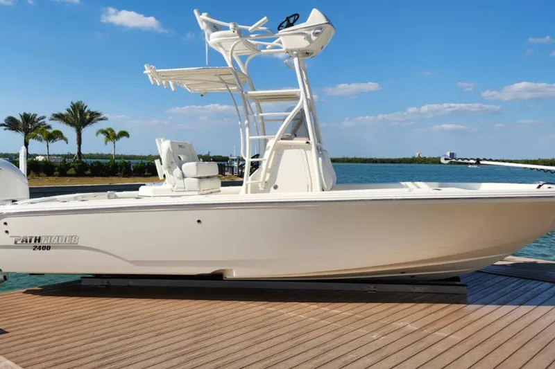 Slide: The Image of 2024 Pathfinder 2400 Open boat docked by the water under a clear blue sky. - 1