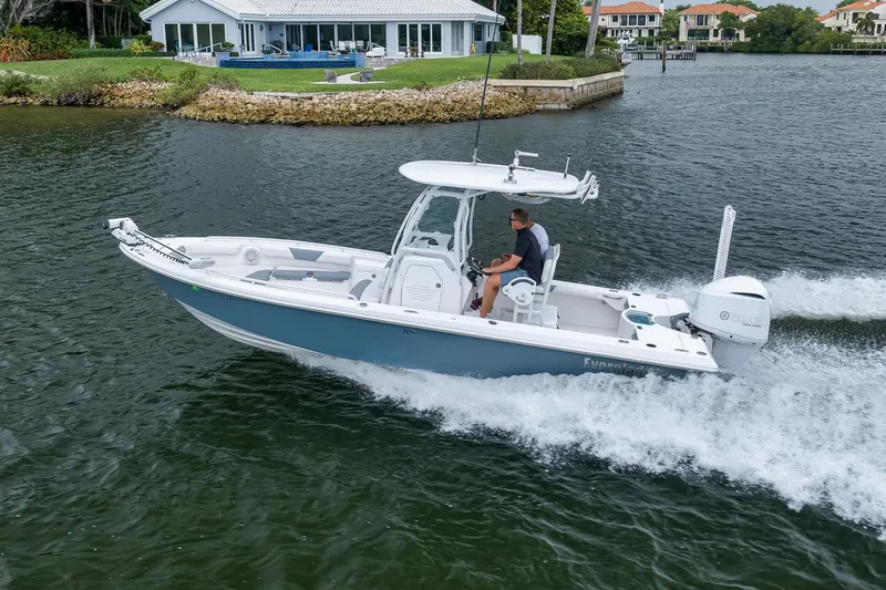 The Image of 2018 Everglades 243 Center Console boat cruising on a scenic waterway near waterfront homes. - 1
