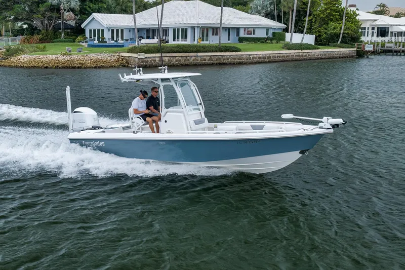 Slide: The Image of 2018 Everglades 243 Center Console boat cruising on a scenic waterway near waterfront homes. - 21