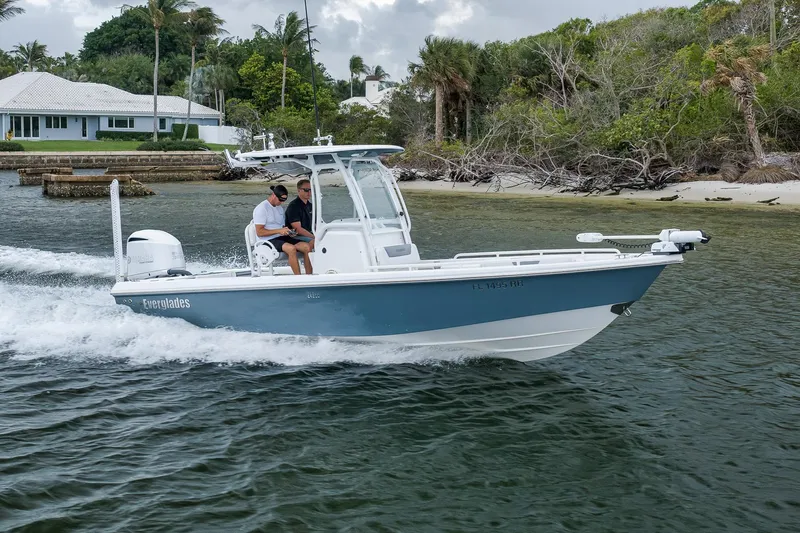 Slide: The Image of 2018 Everglades 243 Center Console boat cruising near a tropical shoreline. - 22