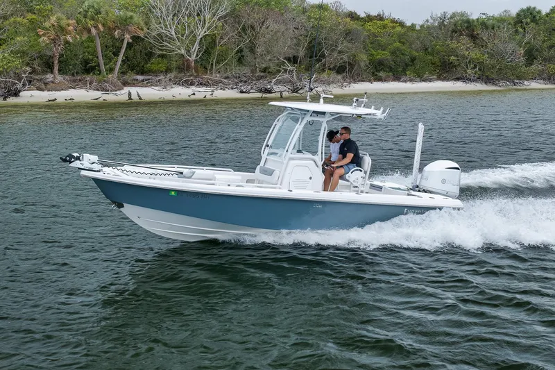 Slide: The Image of 2018 Everglades 243 Center Console boat cruising near a lush shoreline. - 27