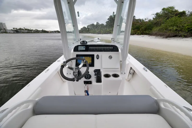 Slide: The Image of 2018 Everglades 243 Center Console boat interior with steering wheel and controls, near sandy shore. - 38