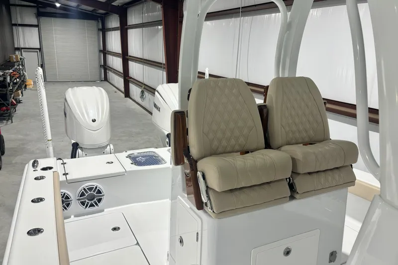 Slide: The Image of 2024 Freeman 28 boat interior with beige seats and dual outboard motors in a garage. - 11