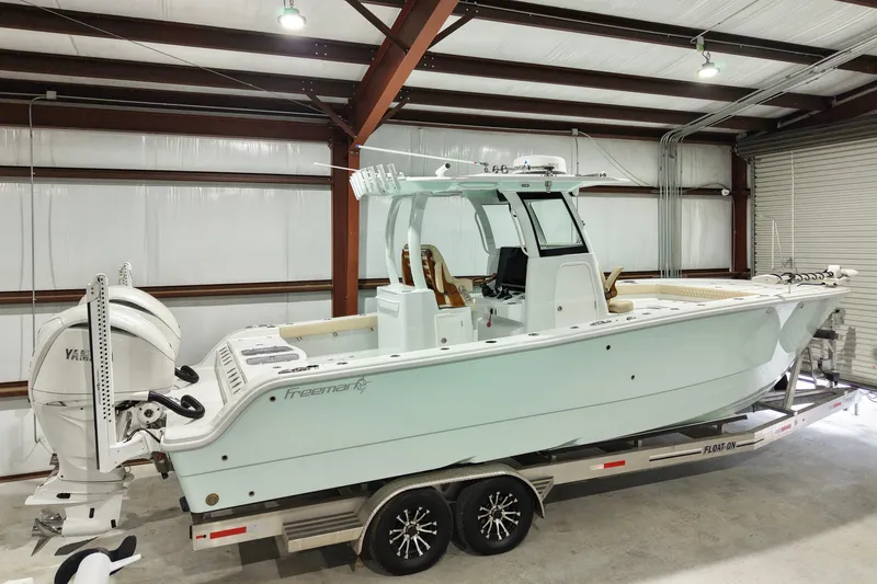 Slide: The Image of 2024 Freeman 28 boat in a warehouse, featuring dual Yamaha engines on a trailer. - 2