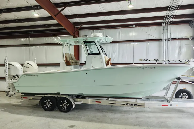 Slide: The Image of 2024 Freeman 28 boat with twin Yamaha engines on a trailer in a warehouse. - 5