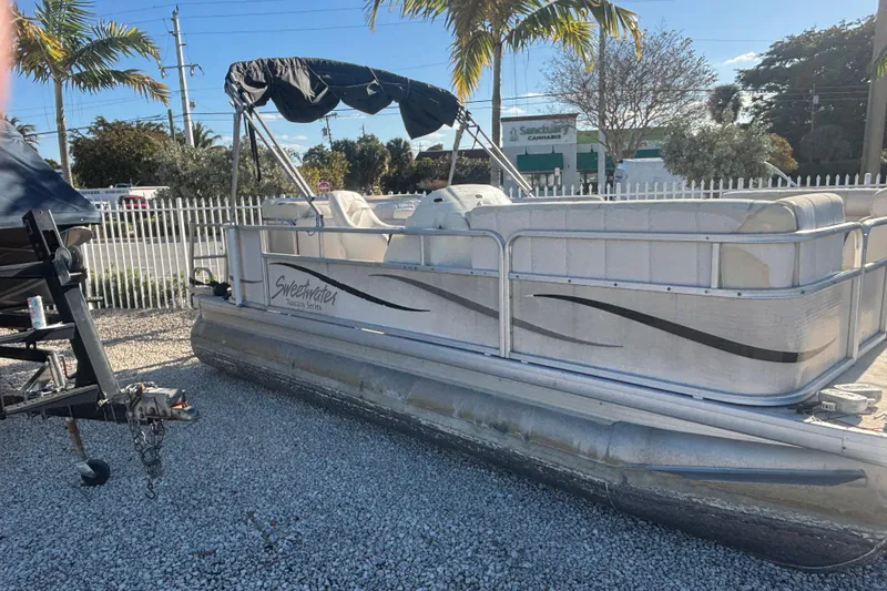 The Image of 2007 Sweetwater 1880 C pontoon boat parked on gravel lot with palm trees. - 1