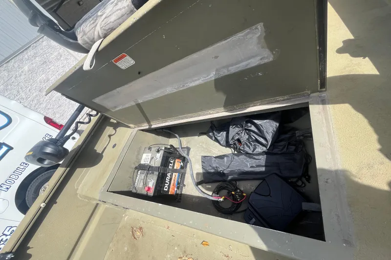 Slide: The Image of Open storage compartment in 2011 Tracker Grizzly 1754 boat with battery and gear. - 11