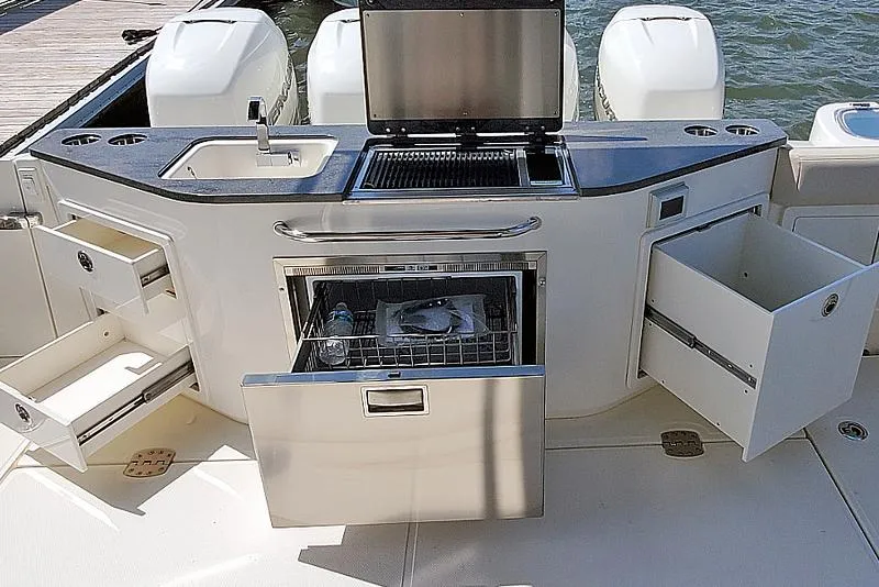 Slide: The Image of Manufacturer Provided Image: 2026 Boston Whaler 405 Conquest boat kitchen with sink, grill, and storage drawers. - 10