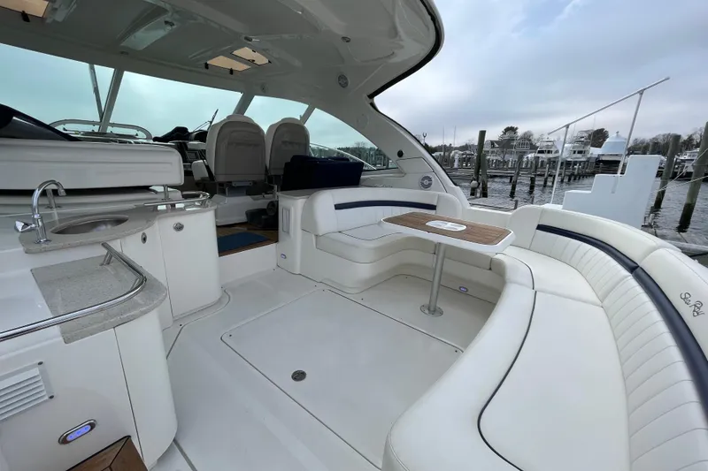 Slide: The Image of 2009 Sea Ray 480 Sundancer yacht interior with seating, table, and kitchenette at a marina. - 3