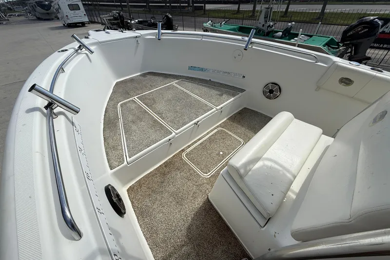 Slide: The Image of 2006 Triton 2690 CC boat interior with seating and rod holders, parked outdoors. - 9
