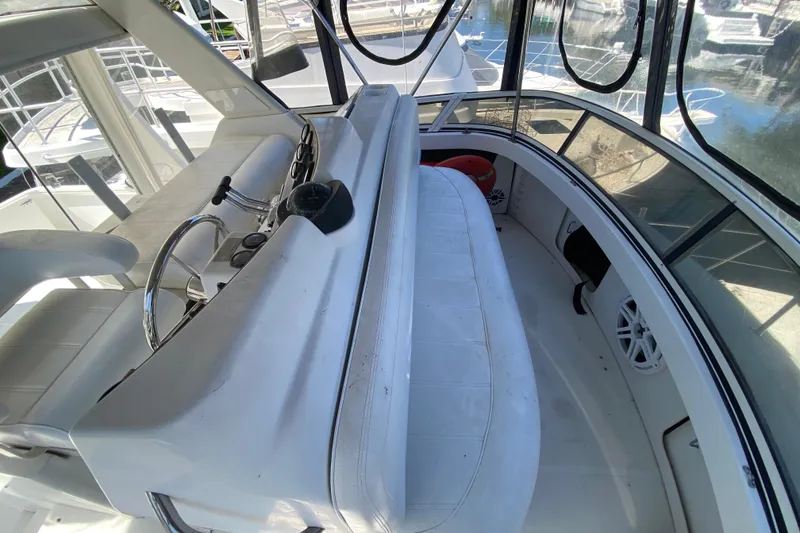 Slide: The Image of 2003 Carver 356 Motor Yacht helm with white seating and steering wheel, docked at marina. - 16