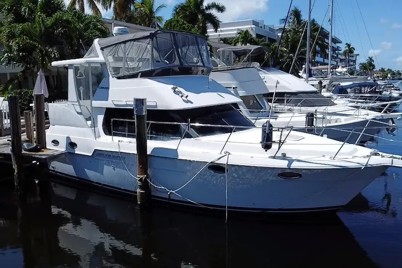 Slide: The Image of 2003 Carver 356 Motor Yacht docked at marina, surrounded by palm trees and other boats. - 5