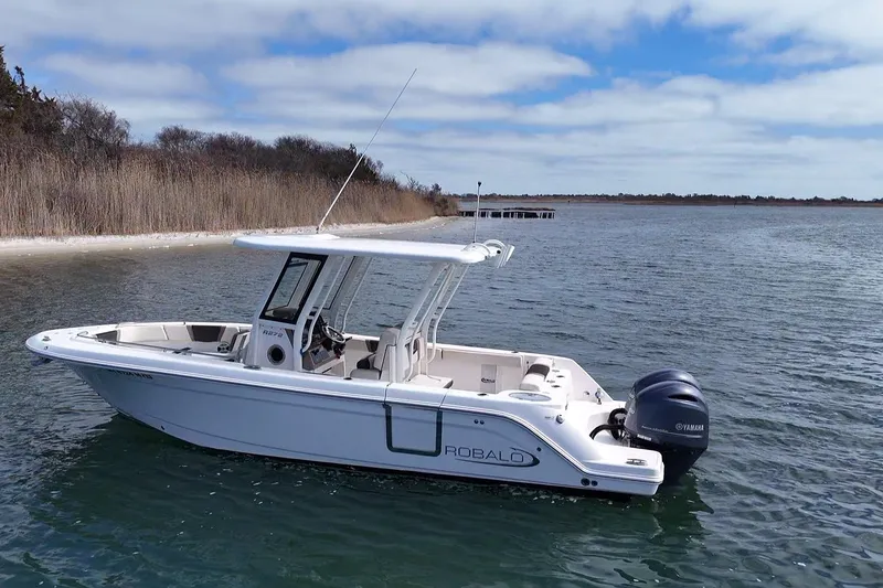 The Image of 2020 Robalo R272 Center Console boat on calm water near a shoreline. - 0