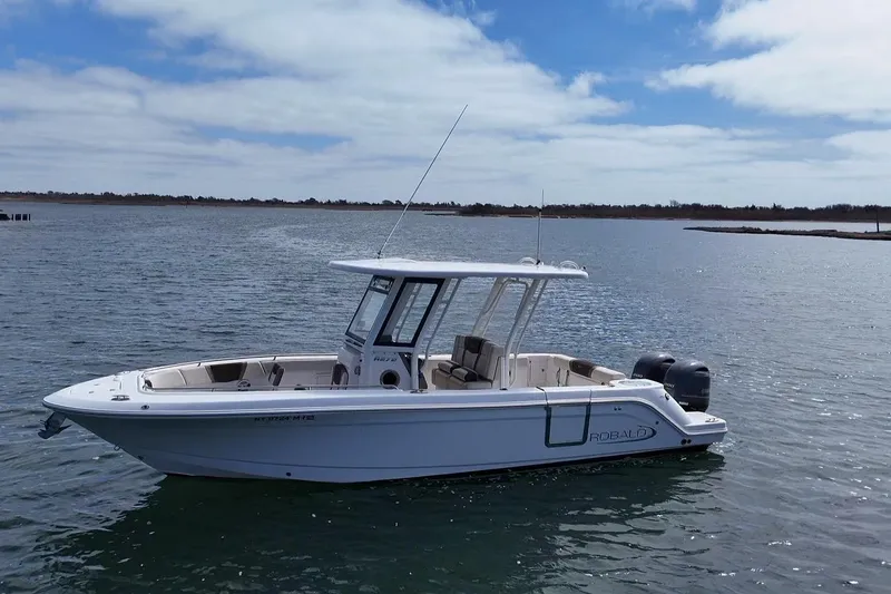 Slide: The Image of 2020 Robalo R272 Center Console boat on calm water under a partly cloudy sky. - 11