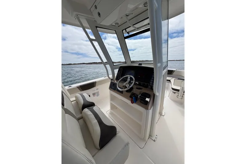 Slide: The Image of 2020 Robalo R272 Center Console boat interior with steering wheel and seating, overlooking water. - 17