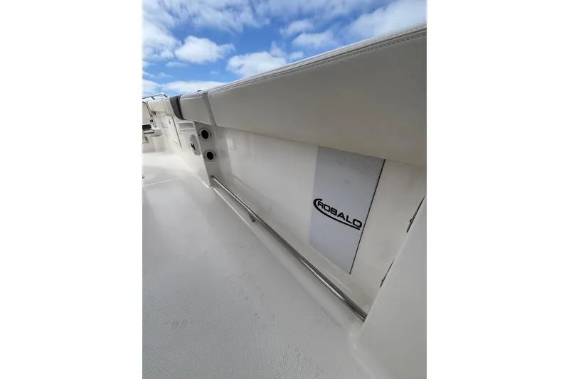 Slide: The Image of 2020 Robalo R272 Center Console interior with logo, white seating, and blue sky. - 36