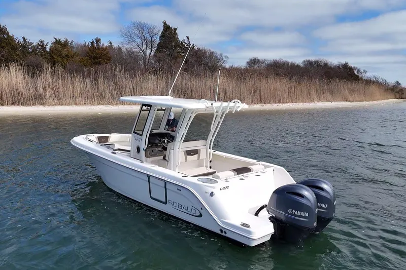 Slide: The Image of 2020 Robalo R272 Center Console boat with twin Yamaha engines on a calm lake. - 4