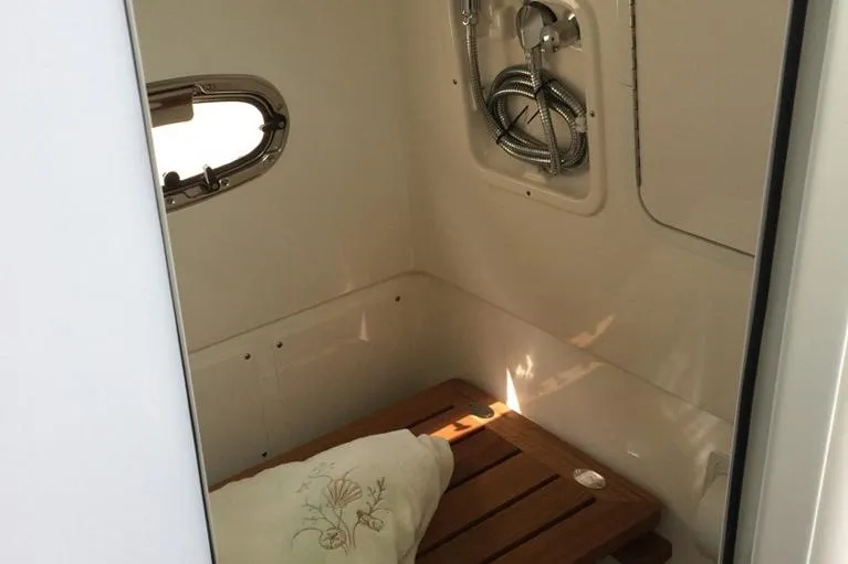 Slide: The Image of Manufacturer Provided Image: 2025 Boston Whaler 380 Outrage cabin interior with wooden bench and porthole. - 19