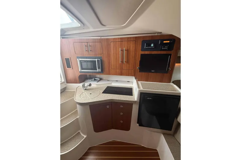Slide: The Image of 2013 Grady-White Express 330 boat kitchen with microwave, sink, and wooden cabinetry. - 19