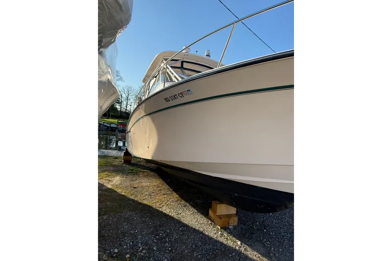 Slide: The Image of 2013 Grady-White Express 330 boat on land, side view with clear sky background. - 2