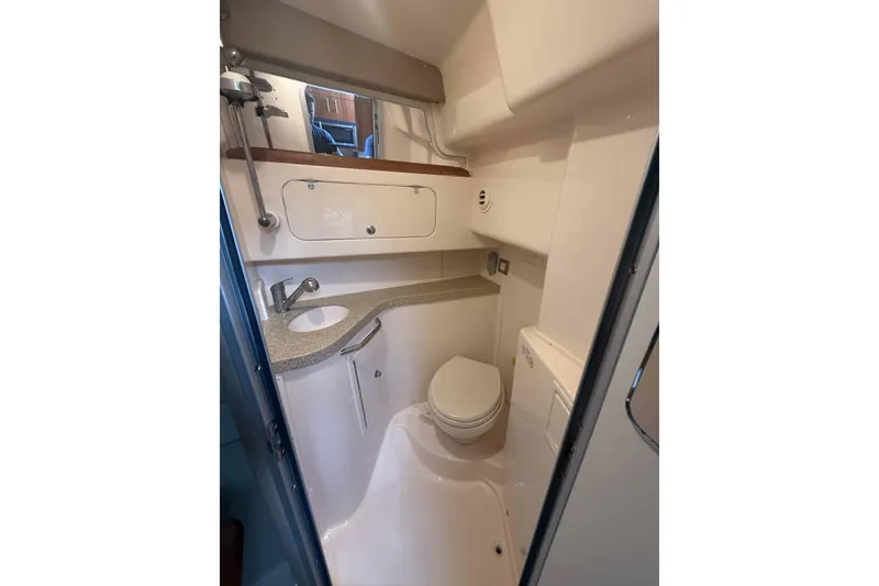 Slide: The Image of Compact bathroom in 2013 Grady-White Express 330 boat, featuring sink, toilet, and storage. - 21