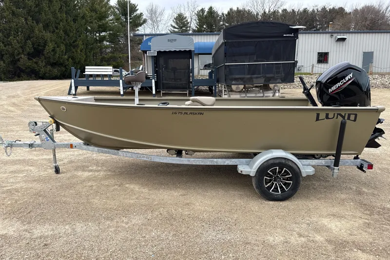 The Image of 2026 Lund 1675 Alaskan Tiller boat on trailer, parked outdoors. - 1